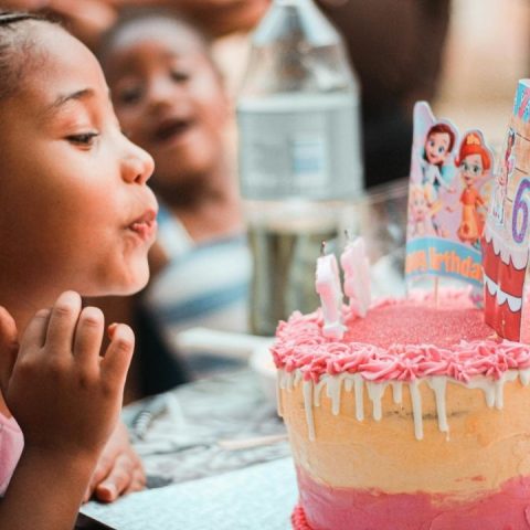 girl blowing out a candle at birthday party