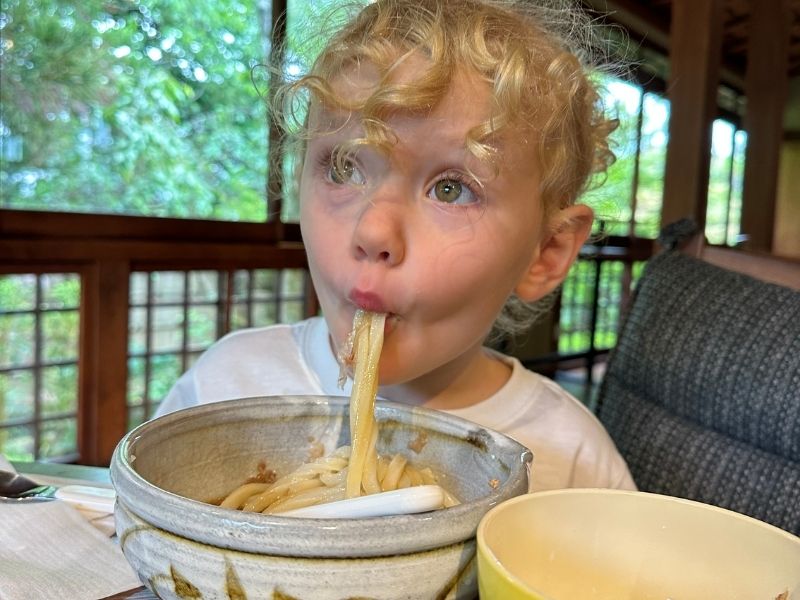 child trying noodles in Japan