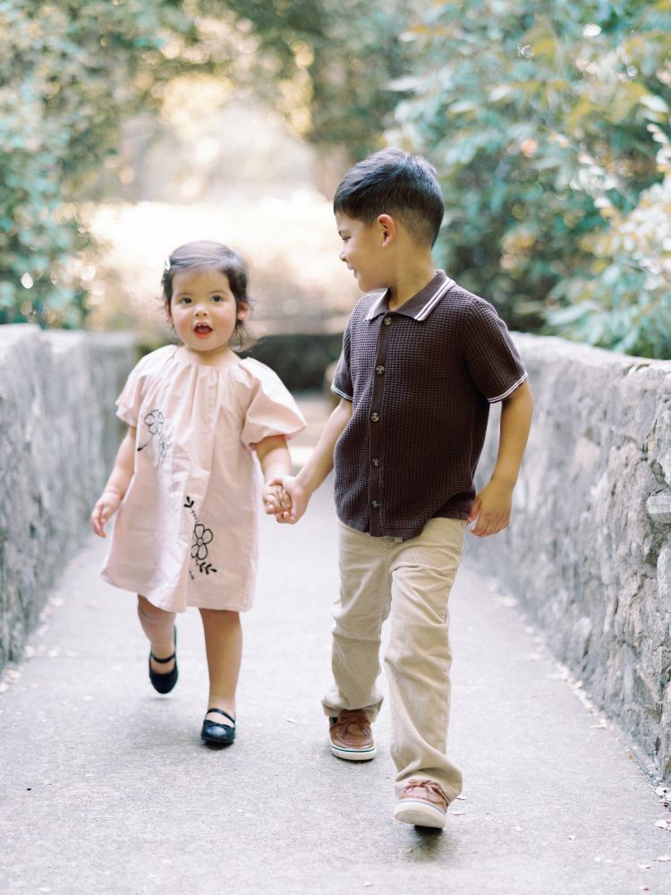 strong little boy leading his baby sister